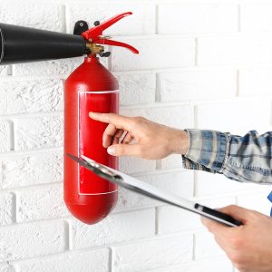 Man inspecting the fire extinguisher against white brick wall background